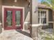 Close-up of a home's double-door entrance with decorative glass and sidelights, complemented by a stone porch and textured column at 10247 Mason Loop, Clermont, FL 34711