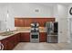 Well-equipped kitchen featuring stainless steel appliances, wooden cabinetry, and tile floors offering a functional cooking space at 1113 Hawthorne Cove Dr, Ocoee, FL 34761
