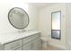 Bathroom with gray vanity, round mirror, glass enclosed shower, and a frosted window at 1204 Duncan Ct, Longwood, FL 32779