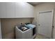 Bright laundry room featuring new front-load washer and dryer plus overhead cabinets at 12126 Diedra Ct, Orlando, FL 32825