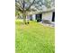 Grassy backyard with AC units, patios, and mature tree providing shade at 14033 Turning Leaf Dr, Orlando, FL 32828