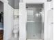 Clean bathroom features a toilet, wall storage, a modern glass-enclosed shower, and white tiling at 141 S Central Ave, Apopka, FL 32703
