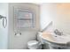 Small, classic white bathroom featuring a pedestal sink and toilet beneath a bright window at 141 S Central Ave, Apopka, FL 32703