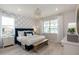 Serene bedroom features a blue upholstered bed, stylish wallpaper, and two windows that fill the room with natural light at 2333 Daisy Tree Rd, St Cloud, FL 34771