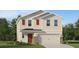 Charming two-story home featuring a two-car garage, red door, and a well-maintained lawn with shrubbery at 4078 Old Mill Rd, Haines City, FL 33844