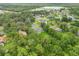 An aerial view of a neighborhood showing numerous houses and mature trees, and a lake in the distance at 4528 Yorkshire Ln, Kissimmee, FL 34758