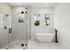 A bright bathroom featuring a glass enclosed shower, soaking tub and three windows at 4528 Yorkshire Ln, Kissimmee, FL 34758