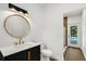 Modern bathroom featuring a black vanity with gold hardware, and a round mirror at 460 W Palm Valley Dr, Oviedo, FL 32765
