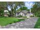 Beautiful white home with a lush green lawn, mature trees, and a long driveway to a side garage at 460 W Palm Valley Dr, Oviedo, FL 32765