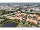 Aerial view of a community with orange roof buildings, a pond, and green spaces at 5447 Vineland Rd # 1308, Orlando, FL 32811