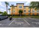 Exterior view of condo building with reserved parking spaces, a car, and landscaping at 5447 Vineland Rd # 1308, Orlando, FL 32811