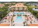 Aerial view of a large community pool with lounge chairs, palm trees, and a lake nearby at 5447 Vineland Rd # 1308, Orlando, FL 32811