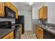 Well-equipped kitchen featuring black appliances, tile backsplash, and wood cabinetry at 6088 Westgate Dr # 201, Orlando, FL 32835