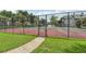 View of a fenced in tennis court with green turf and a red clay surface at 6088 Westgate Dr # 201, Orlando, FL 32835