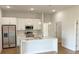 Modern kitchen with stainless steel appliances, a central island with quartz countertop, and elegant pendant lights at 6741 Heavitree Dr, Sebring, FL 33876