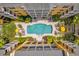 Aerial view of a community pool, surrounded by lounge chairs, lush landscaping, and yellow condos at 860 N Orange Ave # 306, Orlando, FL 32801
