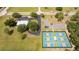 Aerial view featuring tennis courts, parking, and a building surrounded by lush greenery and trees at 8600 Castile Rd, Sebring, FL 33876