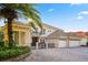 An attractive two-story house boasts a tile roof, a gated entrance, and a three-car garage with a brick-paved driveway at 9128 Phillips Grove Ter, Orlando, FL 32836