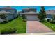 Charming home boasts a manicured lawn, brick driveway, and attached two-car garage at 9971 Beach Port Dr, Winter Garden, FL 34787