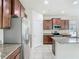 Modern kitchen with granite countertops and stainless steel appliances, featuring brown cabinets and tile flooring at 9971 Beach Port Dr, Winter Garden, FL 34787