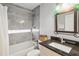 Modern bathroom with tile shower and tub, granite countertop, and decorative mirror and light fixture at 1111 High Vista Dr, Davenport, FL 33837