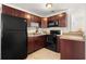 Compact kitchen featuring dark wood cabinetry, granite countertops, and modern black appliances at 1125 Emerald Dr, Mount Dora, FL 32757