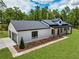 Aerial view featuring attached garage, lush lawn, wooded backdrop, and light-colored modern farmhouse design at 12193 Sw 69 Pl, Ocala, FL 34481