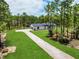 Aerial view of home featuring a long driveway, lush lawn, and wooded backdrop, creating a private oasis at 12193 Sw 69 Pl, Ocala, FL 34481