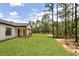 Back exterior corner of home showing wooded backdrop, board and batten siding, and a well-manicured lawn at 12193 Sw 69 Pl, Ocala, FL 34481