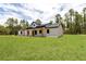 Side view of a single-story home with a lush green lawn, wooded backdrop, and light-colored exterior at 12193 Sw 69 Pl, Ocala, FL 34481