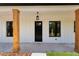 Front door view with black craftsman-style door, windows, stained wood columns, and a hanging light fixture at 12193 Sw 69 Pl, Ocala, FL 34481