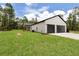Exterior shot of the home's garage featuring gray doors, board and batten siding, and a well-manicured lawn at 12193 Sw 69 Pl, Ocala, FL 34481