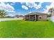 View of the home's backyard, featuring a spacious lawn and an enclosed screened lanai at 12845 Sawgrass Pine Cir, Orlando, FL 32824
