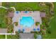 Aerial view of community pool, umbrellas and lounge chairs surrounded by tropical landscaping at 12845 Sawgrass Pine Cir, Orlando, FL 32824