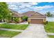 Inviting single-story home boasting a two-car garage, lush lawn, and complemented with tropical palm trees at 12845 Sawgrass Pine Cir, Orlando, FL 32824
