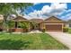 Charming one-story home featuring a well-manicured lawn and beautiful tropical landscaping at 12845 Sawgrass Pine Cir, Orlando, FL 32824