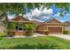 Charming single-story home with a well-manicured lawn, complemented by white rock landscaping and palm trees at 12845 Sawgrass Pine Cir, Orlando, FL 32824