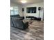 Cozy living room features wood-look flooring, a comfortable reclining sofa, and a large television at 12845 Sawgrass Pine Cir, Orlando, FL 32824