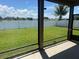 Screened-in patio with a view of the fenced backyard and lake at 12845 Sawgrass Pine Cir, Orlando, FL 32824