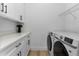 Bright laundry room features white cabinets, quartz countertops, updated appliances and shelving for storage at 13393 Sw 484 Hwy, Ocala, FL 34481