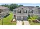 This two-story gray townhome features two-car garage, shutters, solar panels, and a well-maintained lawn at 1396 Mirabella Cir, Davenport, FL 33897