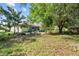 A spacious backyard with trees and foliage, a screened porch and partial view of the home at 14 Sequoia Way, Kissimmee, FL 34758
