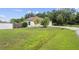 Spacious front yard with a well-maintained lawn, mature trees, a privacy fence, and a paved driveway at 14 Sequoia Way, Kissimmee, FL 34758