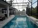Inviting screened-in pool area with a spa, perfect for relaxation, set against a backdrop of lush greenery and blue skies at 14955 Lebeau Loop, Winter Garden, FL 34787