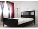 Bedroom features a dark wood bed frame, neutral tile, and curtains on a window at 1504 Virginia Ave # 105, Daytona Beach, FL 32114