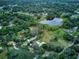 Expansive wooded property featuring a pond, main house, and outbuildings amid lush greenery and mature trees at 205 Elaine Pl, Chuluota, FL 32766
