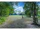 Spacious backyard featuring a large grassy area, mature trees, and a green outbuilding at 205 Elaine Pl, Chuluota, FL 32766