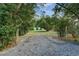 Secluded backyard gate, revealing a spacious yard with lush greenery and storage buildings at 205 Elaine Pl, Chuluota, FL 32766
