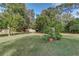 Private backyard area with lush green grass, mature trees, and potted plants near a tree stump at 205 Elaine Pl, Chuluota, FL 32766