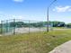 Community tennis court surrounded by a chain link fence with a view of mature trees at 2409 Pinyon Ct, Kissimmee, FL 34746